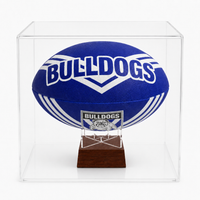 A blue and white Bulldogs AFL ball mounted on a small wooden display stand inside a clear acrylic cube case, photographed against a light gray studio background.