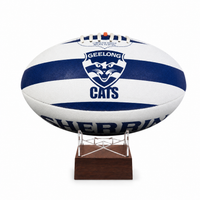 A white and navy blue Geelong Cats AFL ball displayed on a small wooden stand against a plain white background.
