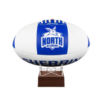 A cremation urn designed and made from an Australian football, with a blue and white North Melbourne Kangaroos theme, mounted on a wooden stand.
