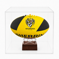 A yellow and black Richmond Tigers rugby ball displayed inside a clear acrylic display case on a wooden stand.