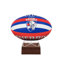 A Western Bulldogs AFL ball urn displayed on a clear acrylic stand with a dark brown wooden base, set against a plain white background.