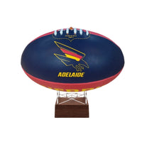 A navy blue Adelaide football ball on a clear acrylic display stand with a dark brown wooden base, featuring the Adelaide Kangaroo logo and 'ADELAIDE' text on a white background.