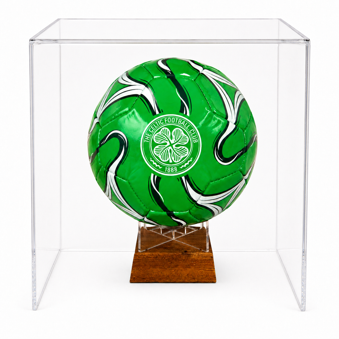 A green soccer ball with white and black swirls and a Celtic FC crest, displayed inside a clear acrylic cube on a wooden stand against a white background.