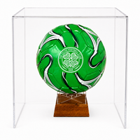 A green soccer ball with white and black swirls and a Celtic FC crest, displayed inside a clear acrylic cube on a wooden stand against a white background.