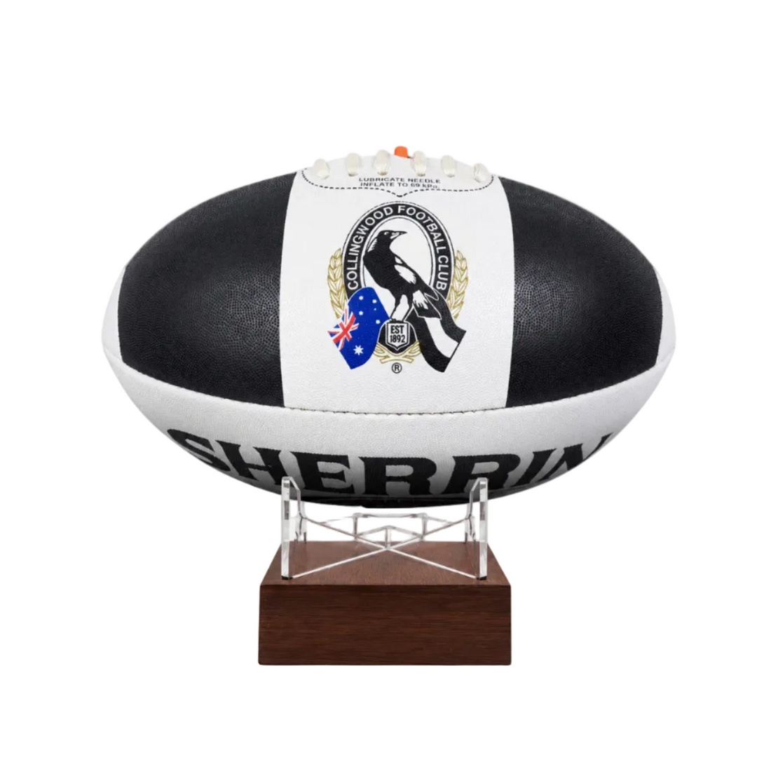 A black and white AFL ball with the Collingwood Football Club logo, displayed on a clear stand with a dark brown wooden base against a white background.