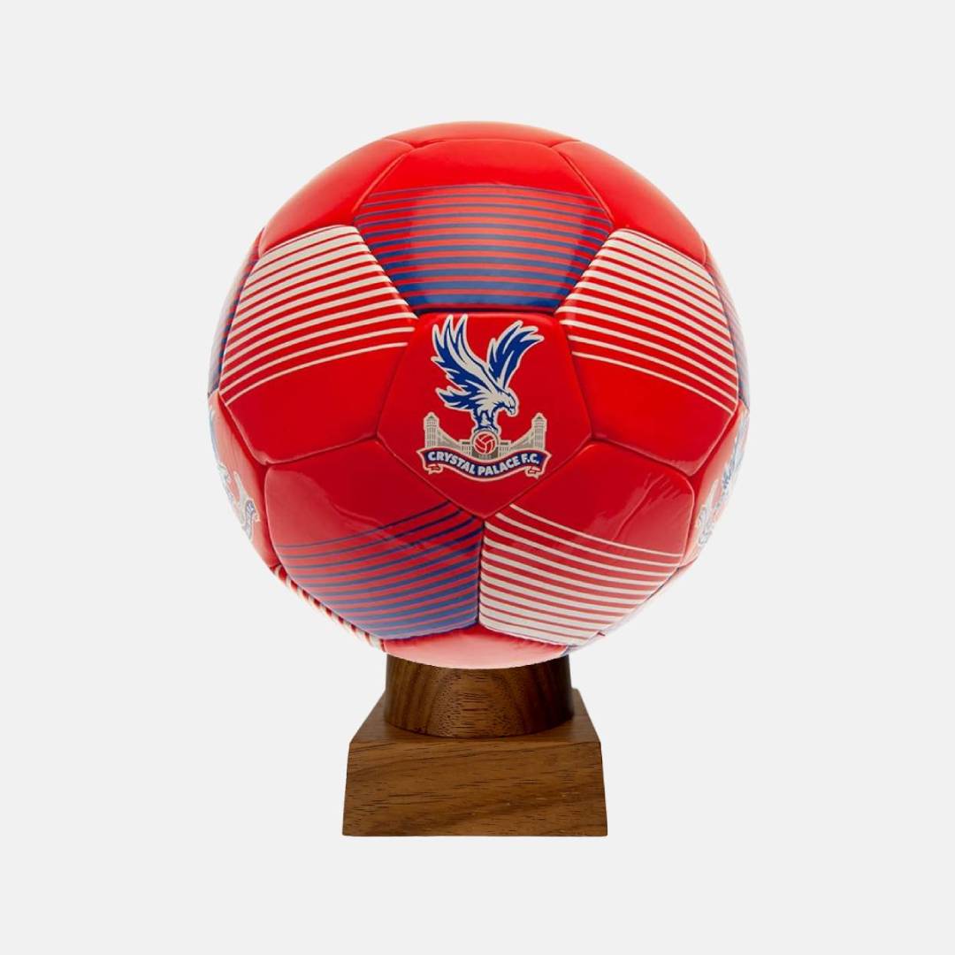 A handcrafted cremation urn made from an authentic Crystal Palace FC soccer ball, displayed on a wooden base.