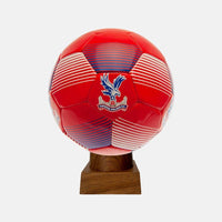 A handcrafted cremation urn made from an authentic Crystal Palace FC soccer ball, displayed on a wooden base.