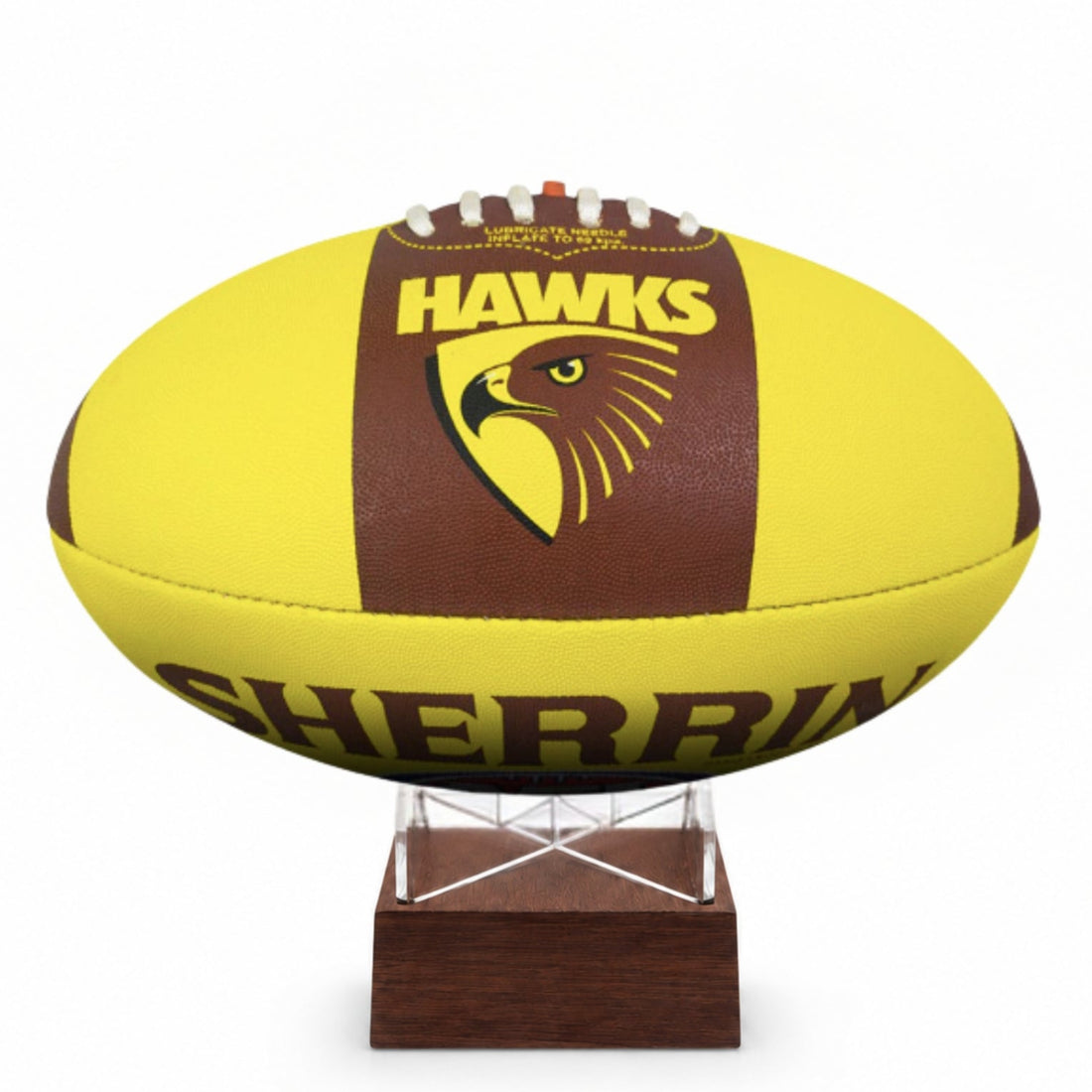 A yellow and brown Sherrin Hawks football displayed on a small wooden stand against a white background.
