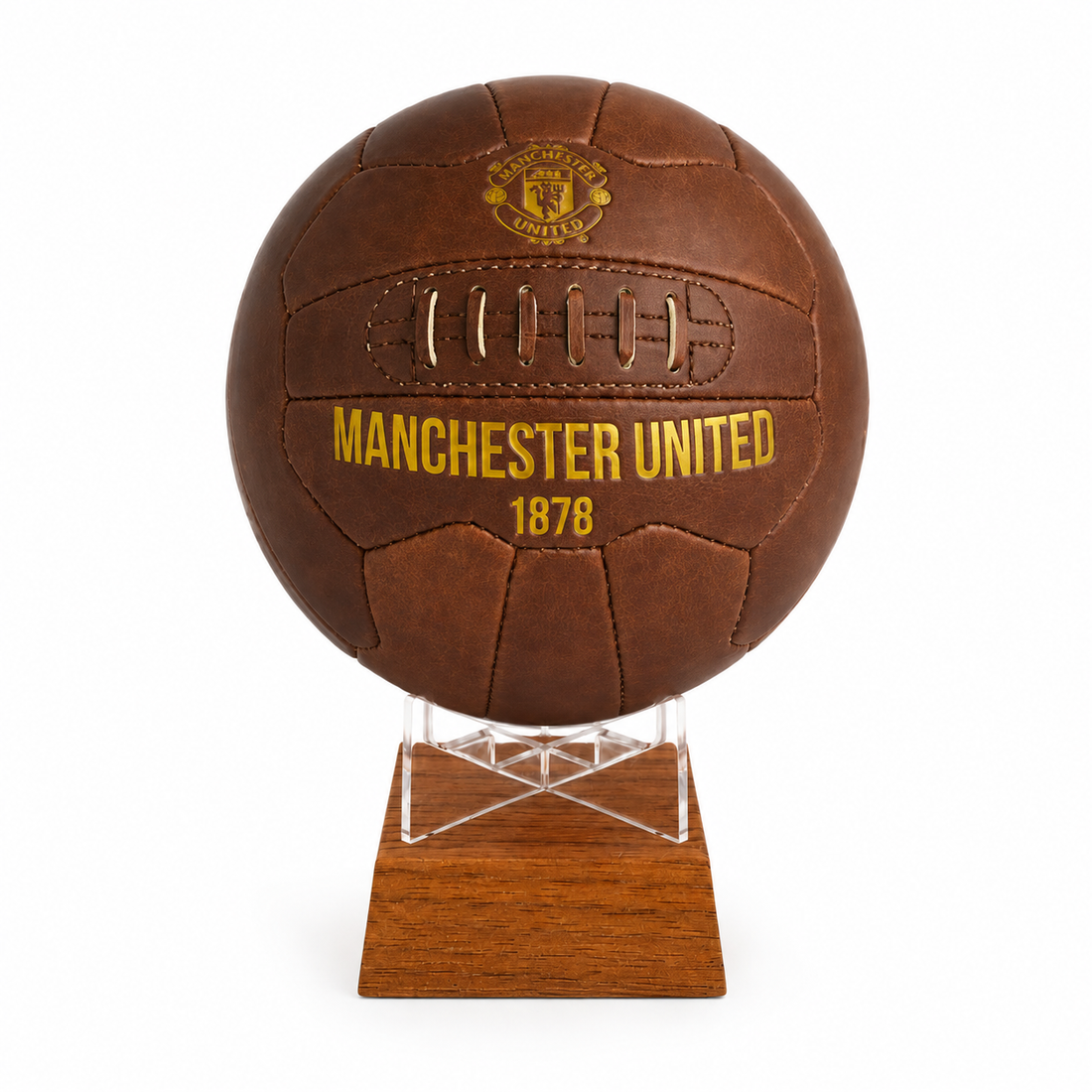 A brown leather Manchester United soccer ball urn mounted on a clear acrylic stand with a wooden base, shown against a plain white background.