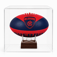 A red and navy blue Melbourne Demons Football Club AFL ball urn  displayed on a clear acrylic stand inside a transparent display case, set against a plain white background.