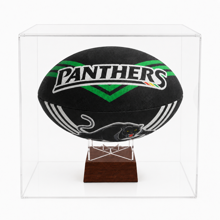 A black Penrith Panthers rugby ball displayed inside a clear acrylic cube case on a dark wood stand, photographed against a clean white background.