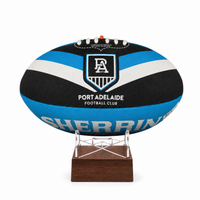 A custom Port Adelaide Football Club rugby ball  urn with a black, blue, and white striped design, displayed on a clear acrylic stand with a dark brown wooden base against a white background.