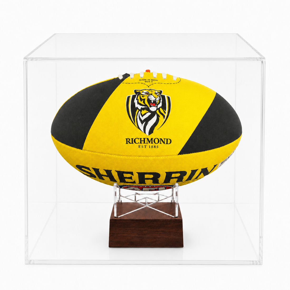 A yellow and black Richmond Tigers rugby ball displayed inside a clear acrylic display case on a wooden stand.
