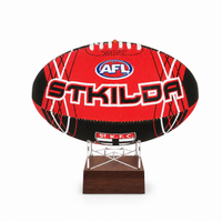 A red and black St Kilda AFL football displayed on a clear stand with a dark wooden base, set against a plain white background.