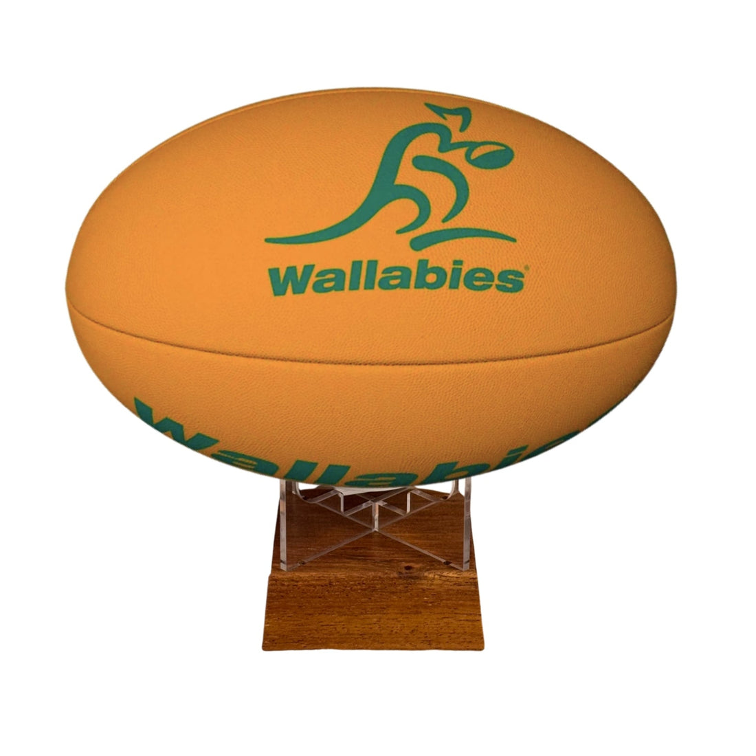 An orange rugby ball with green Wallabies branding, displayed on a small wooden stand against a plain white background.
